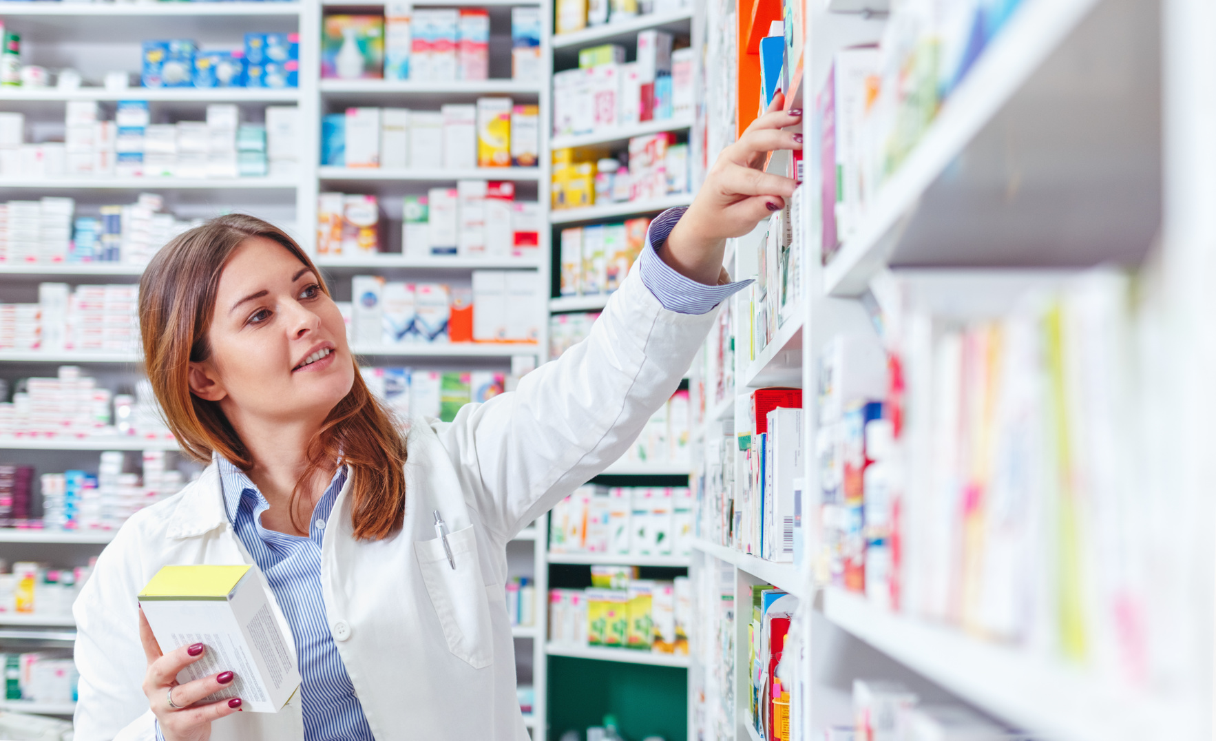 Photo of a professional pharmacist checking stock in an aisle of a local drugstore.